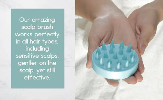 Hands holding a light blue silicone scalp brush with soft bristles for hair care