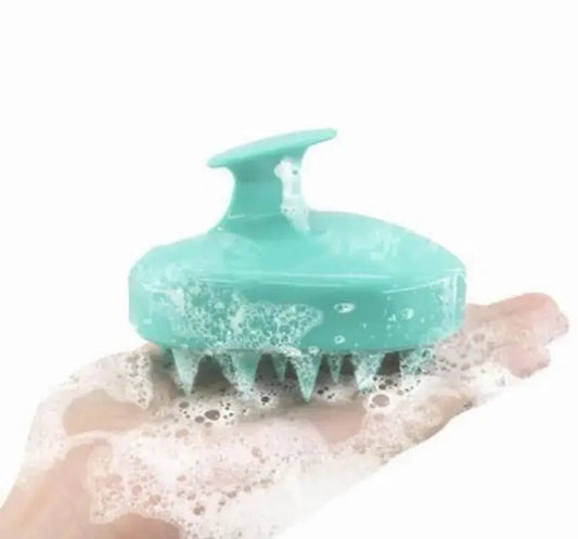Aqua silicone scalp massager brush with handle and soft bristles, covered in foamy soap.