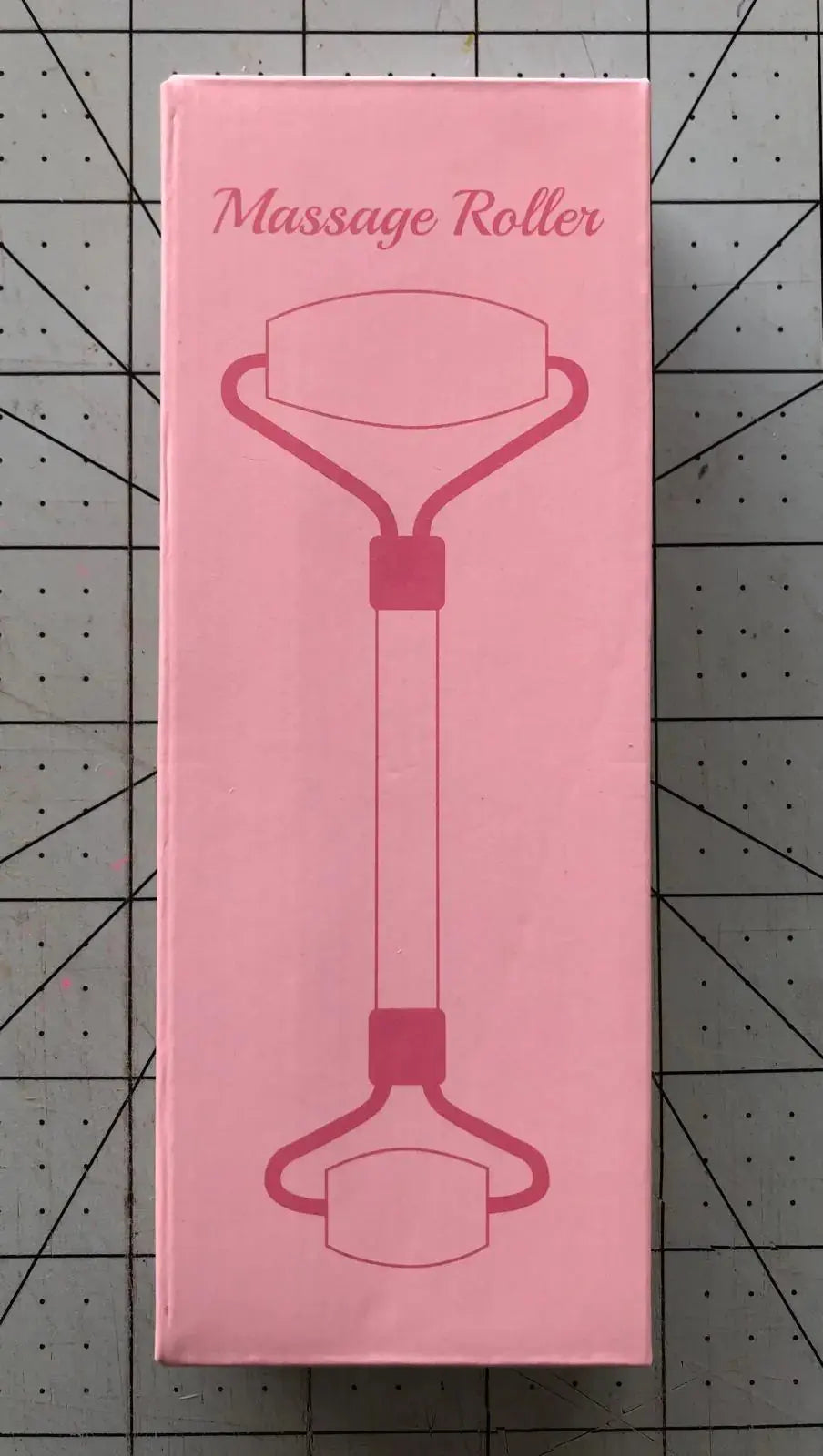 Pink massage roller packaging with illustrated roller design on a grid background