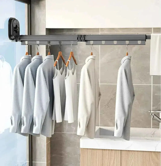 Retractable wall-mounted clothes rack with shirts and tank tops hanging in a modern bathroom