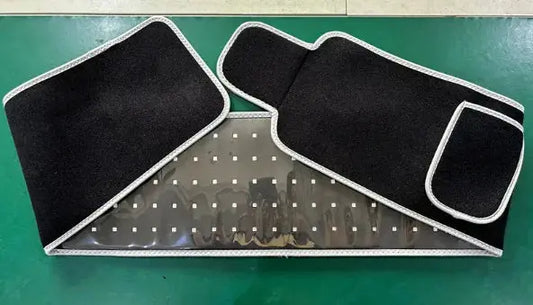 Black adjustable waist belt with hook-and-loop fasteners and transparent section on green surface